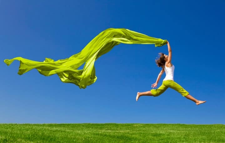 Women jumping with green fabric