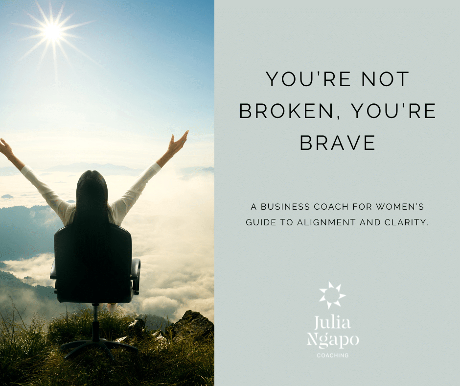 You’re Not Broken, You’re Brave: A Business Coach for Women’s Guide to Alignment and Clarity - Julia Ngapo Coaching - woman seated in office chair on cliff top surveying the vista. Her arms are raised in joy and confidence.